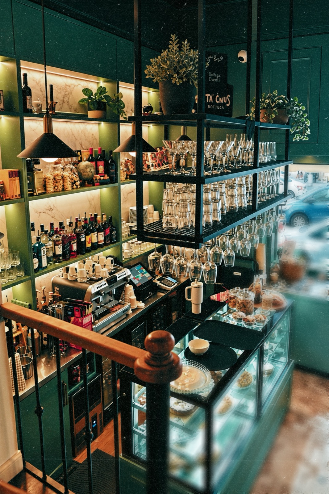 The bar at Bottega Ta’ Ċnus, with shelves of wine, hanging glassware and the pastry counter