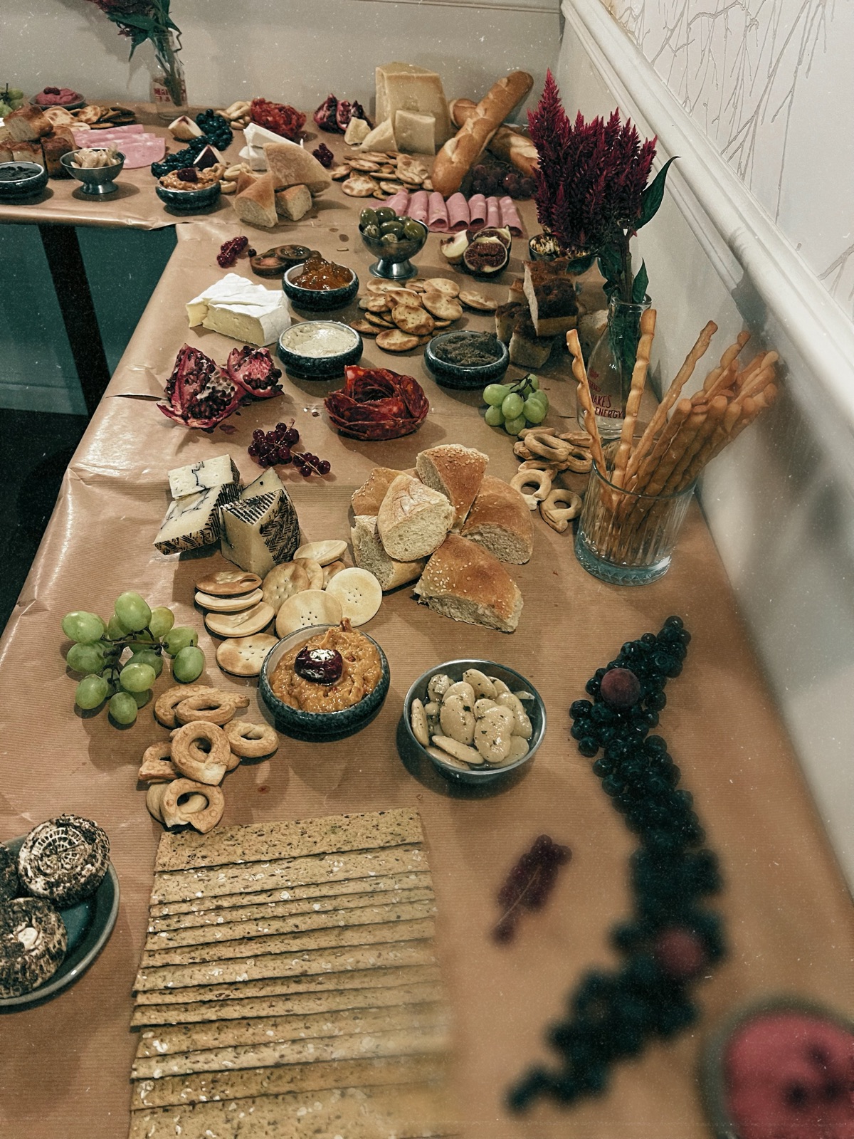A long grazing table laid for a private event, with cheeses, cured meats, dips, bread and grapes