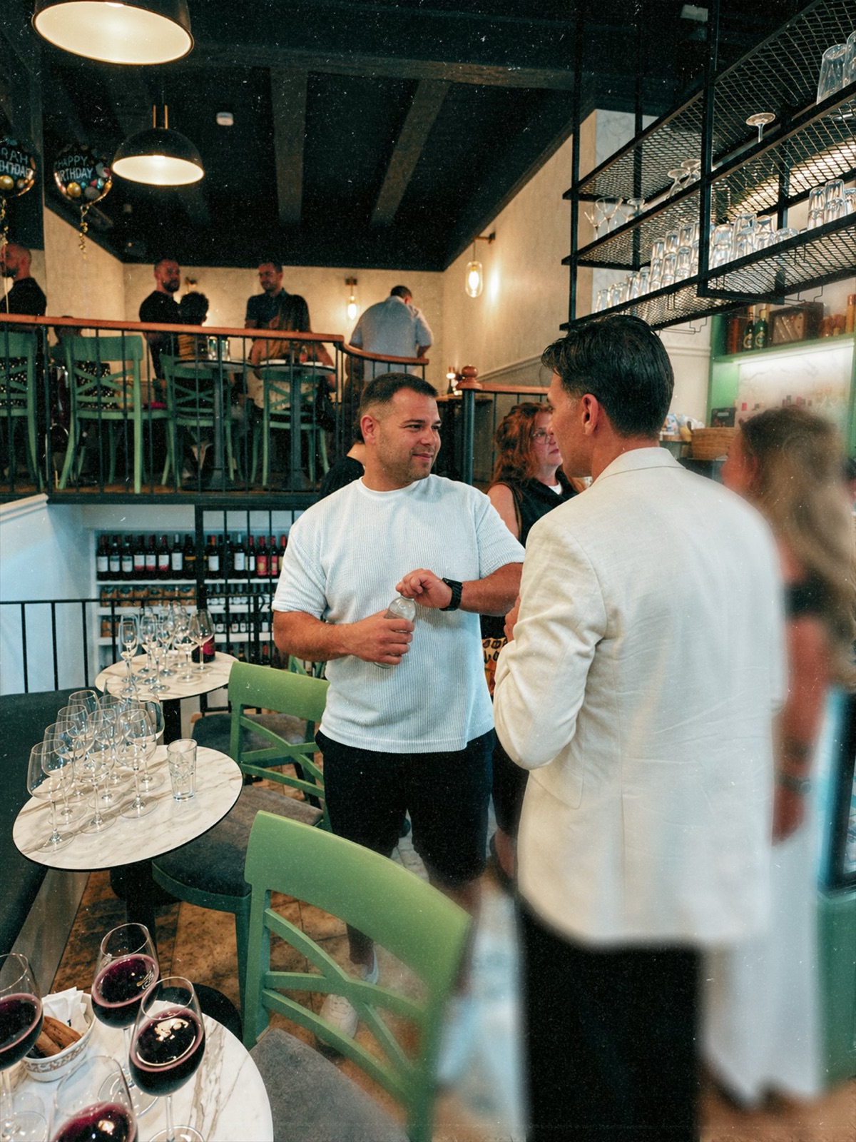 Guests chatting over glasses of red wine inside Bottega Ta’ Ċnus